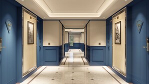 A hotel corridor with blue walls, a tiled floor, and framed pictures on the doors. - Grand Hotel Preanger, Bandung, a Tribute Portfolio Hotel (Bandung)