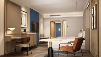 A hotel room with a bed, two chairs, a small table, a TV, and a lamp.