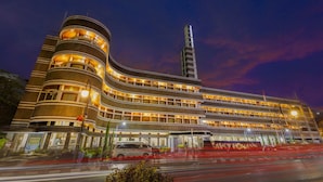 A multi-story hotel with a curved facade, multiple balconies, and a prominent vertical tower. - Hotel Savoy Homann (Bandung)
