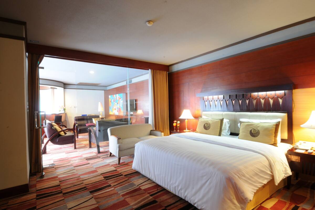 A hotel room with a large bed, a desk, and a chair.