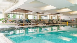 An indoor swimming pool with lounge chairs and potted plants. - Hotel Savoy Homann (Bandung)