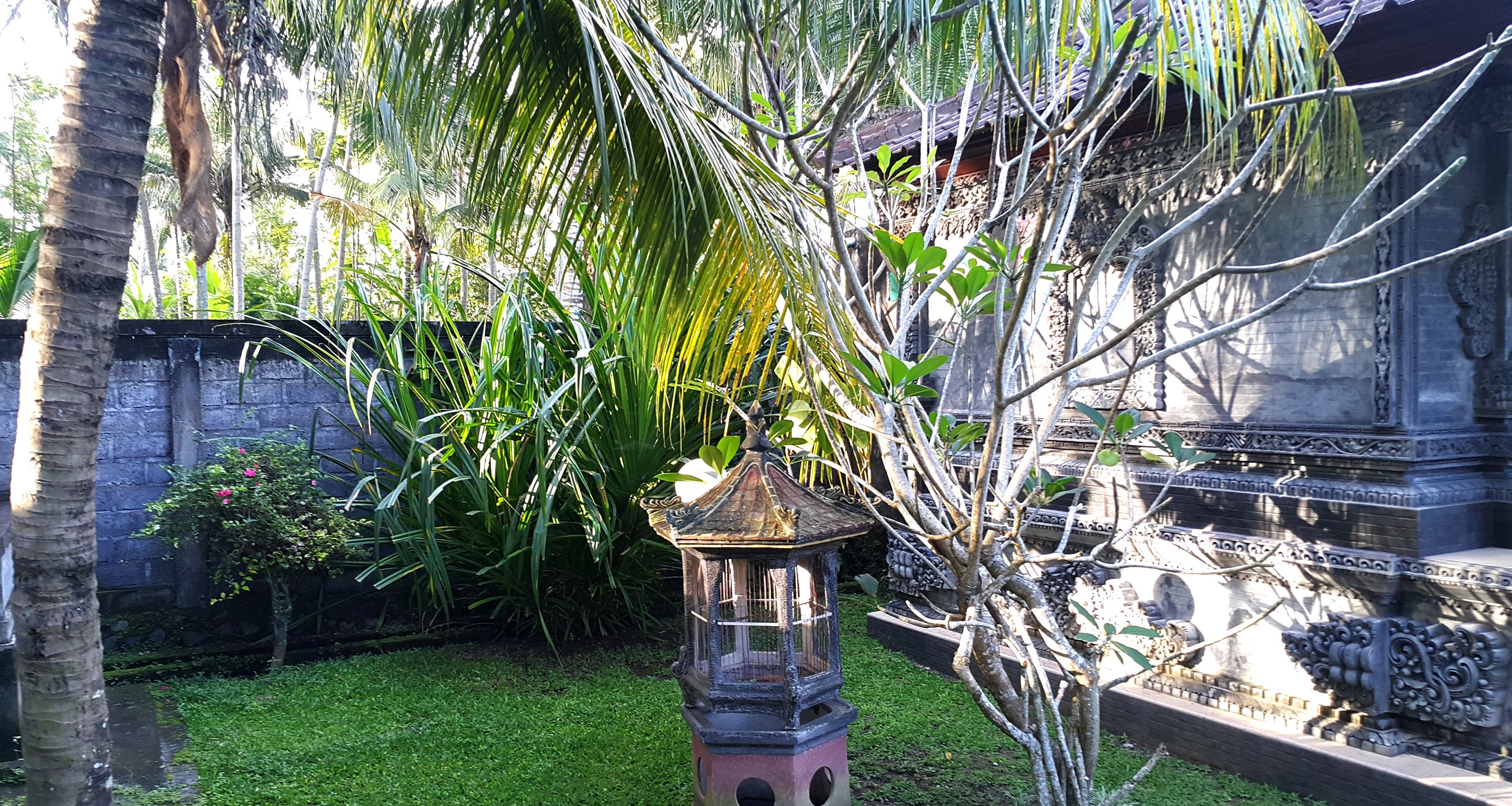 A traditional stone structure with intricate carvings, surrounded by lush greenery and a small water feature.