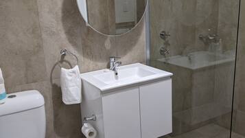 A modern bathroom with a toilet, sink, and glass-enclosed shower.