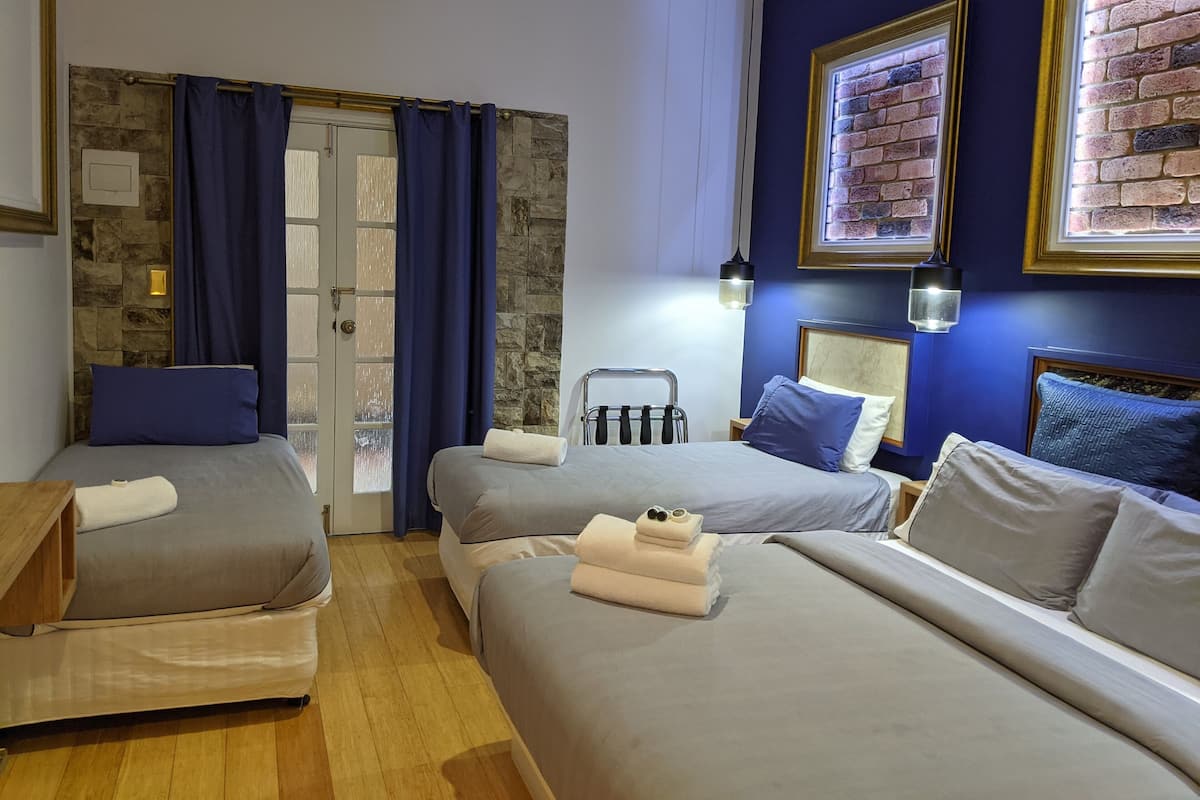 Une chambre d’hôtel avec deux lits, un mur en pierre, une porte avec des rideaux et des tableaux encadrés accrochés au mur.