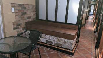 Een gang met een stenen bank, een glazen tafel en stoelen.