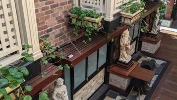 A brick wall with a wooden fence, potted plants, and stone statues.