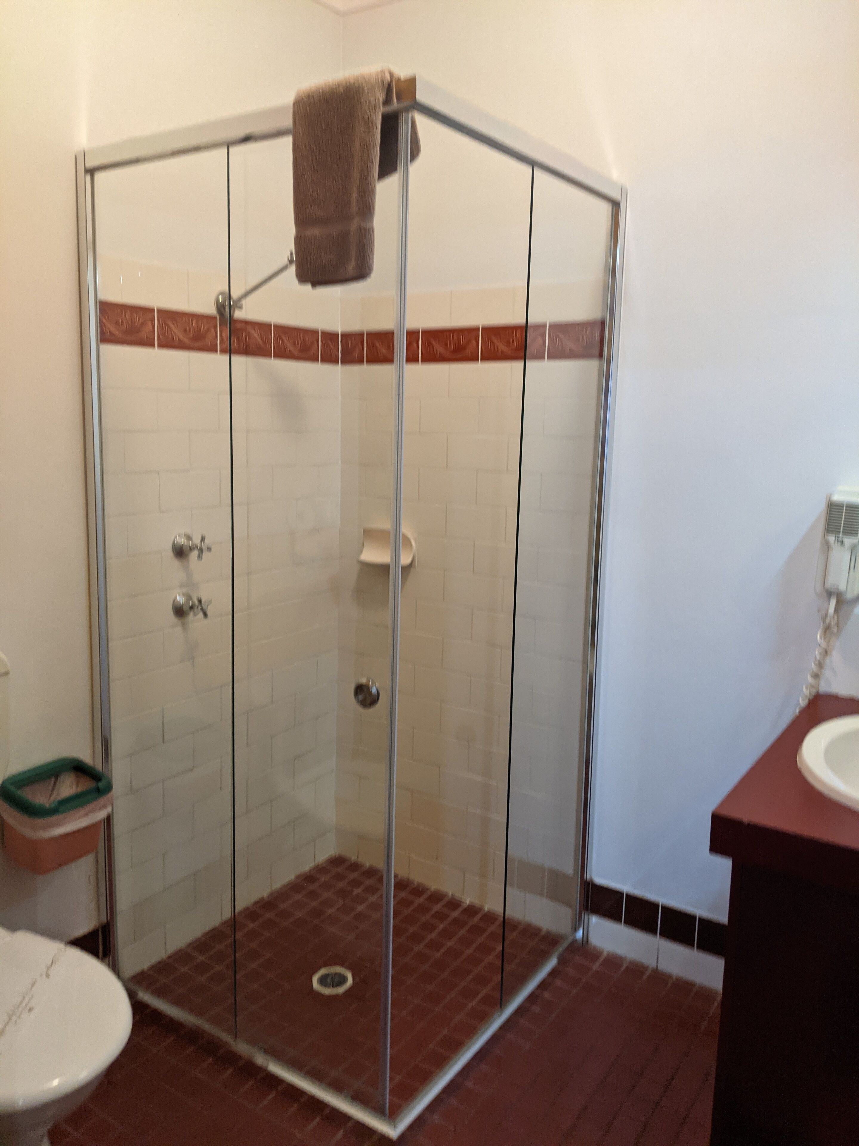 Un baño con ducha de vidrio, inodoro y lavabo.