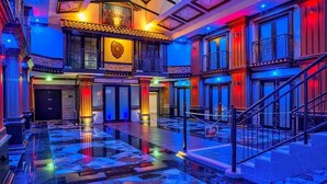 Een ruime lobby met een gepolijste marmeren vloer, een imposante trap en een balkon met versierde leuningen.