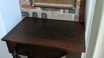 A dark wooden table with a chair in front of a brick wall with a framed sign that reads "Calligraphy Lessons."