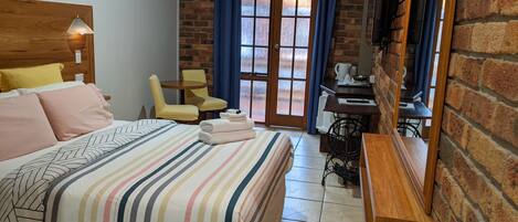 A hotel room with a bed, a chair, a desk, and a window with curtains.
