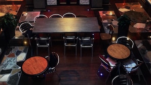 Een ruime lobby met een houten receptiebalie in het midden, verschillende zithoeken en een vloer met een patroon.