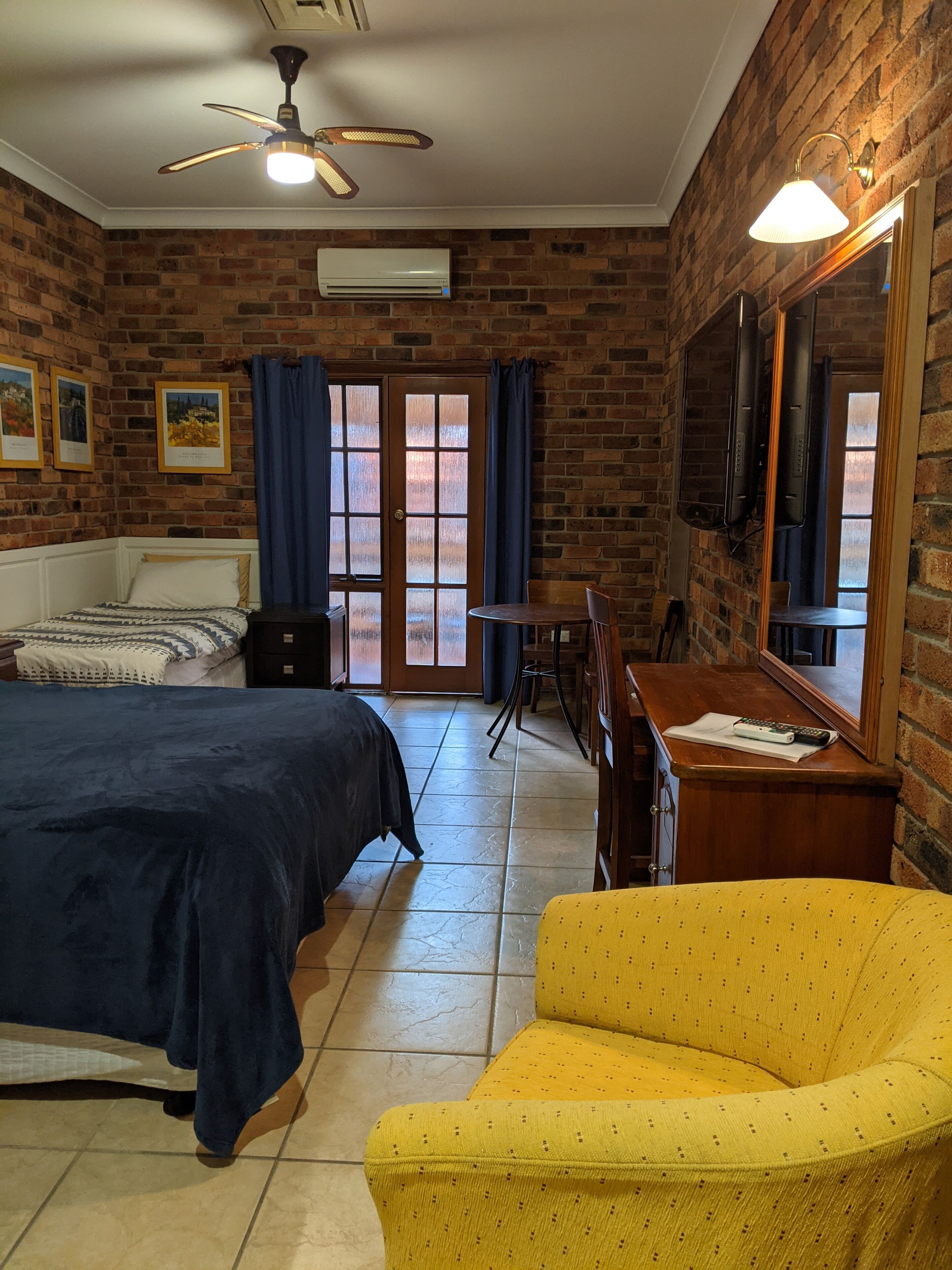 Une chambre d’hôtel équipée d’un lit, d’un bureau, d’une chaise, d’une télévision et d’une grande fenêtre avec des rideaux.