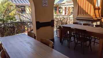 Ein Restaurant mit Holztischen und -stühlen, einem Rauchverbot-Schild und Blick auf Gebäude im Hintergrund.