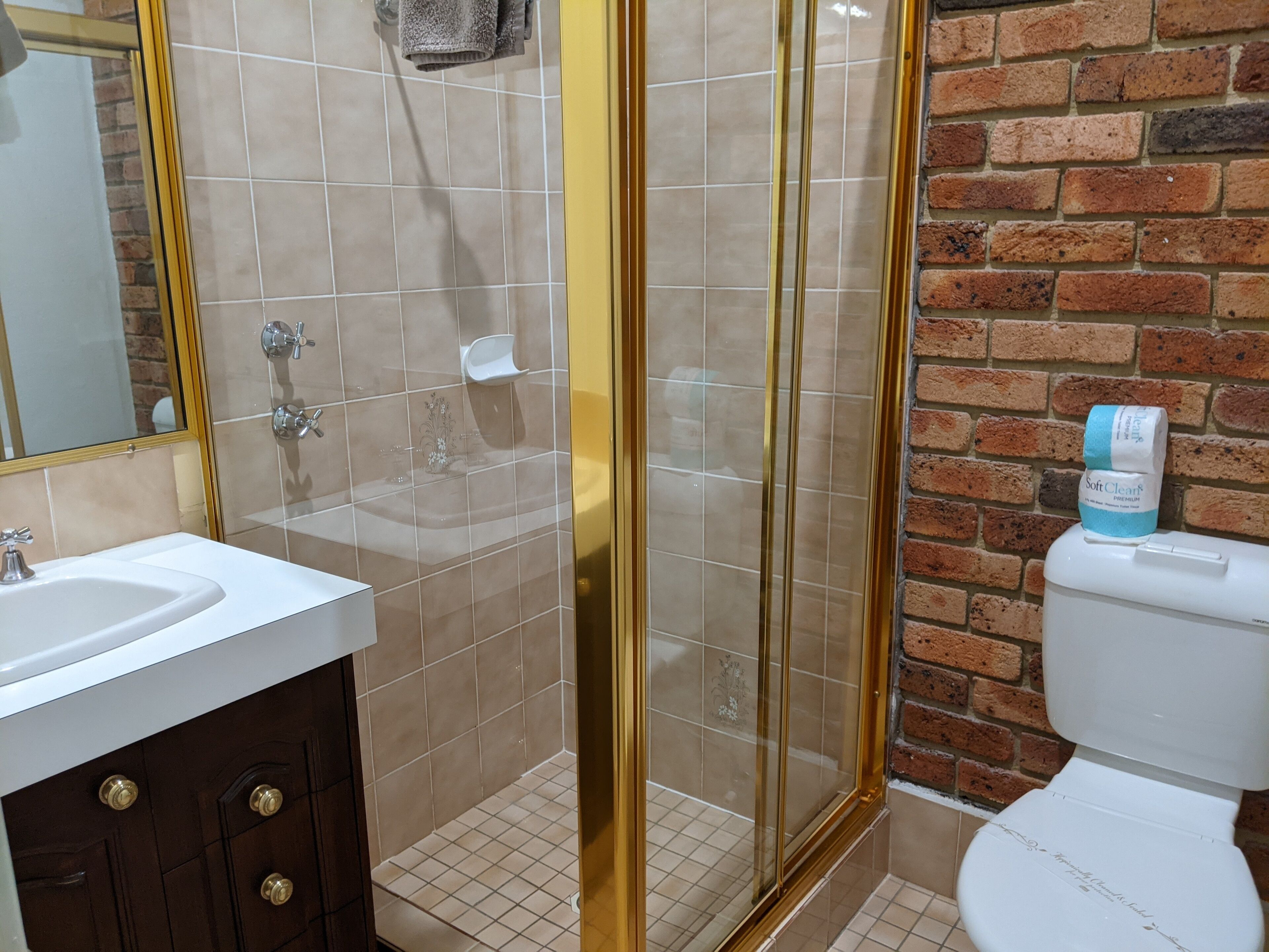 A bathroom with a shower, toilet, sink, and a mirror.
