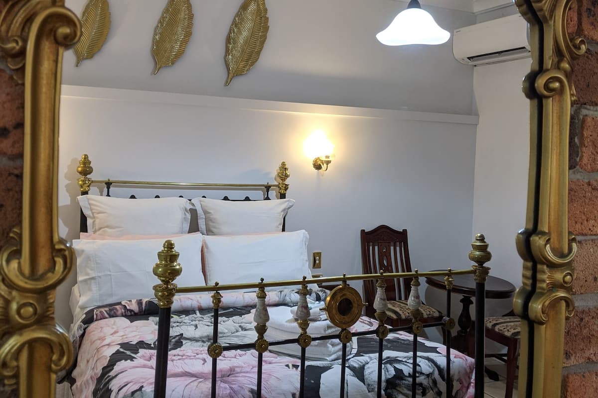 Une chambre à coucher comprenant un lit, une chaise, une lampe fixée au mur et des œuvres d’art décoratives accrochées au mur.