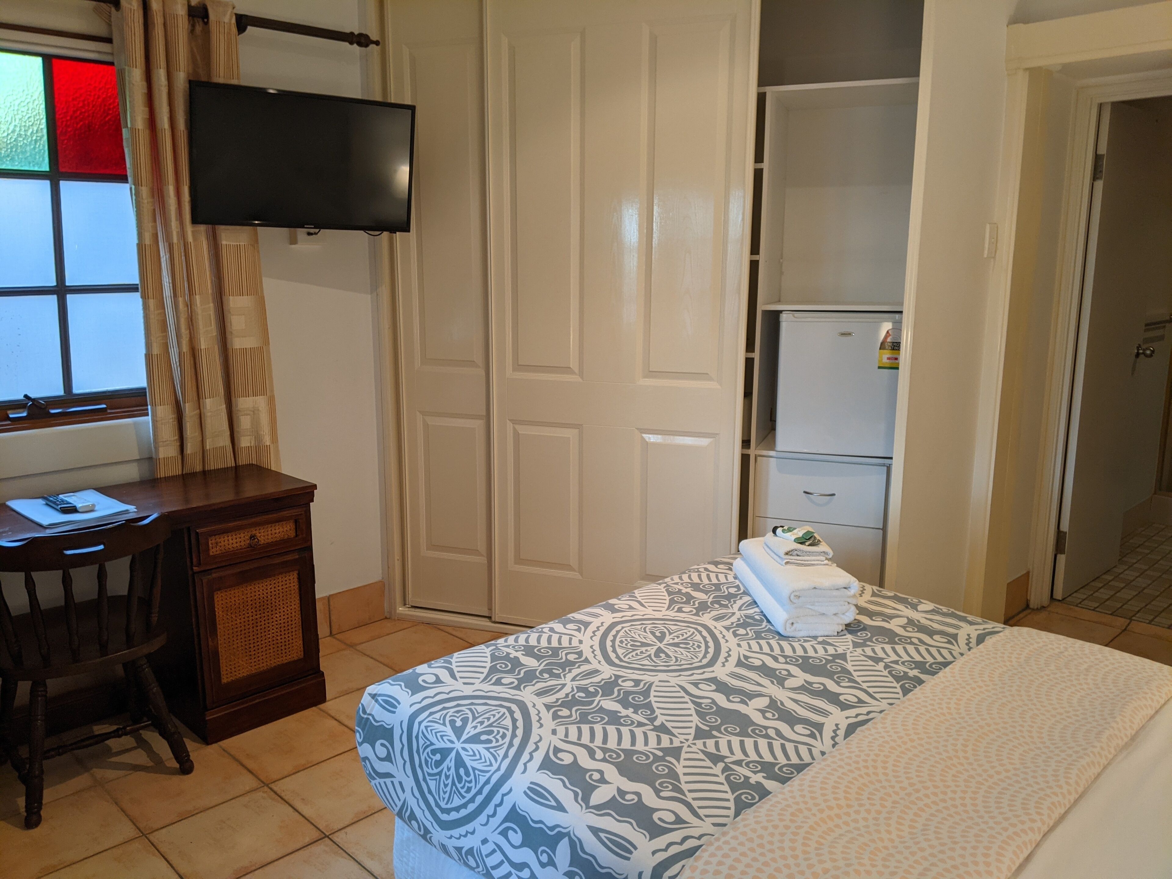 A hotel room with a bed, a desk, a television, and a wardrobe.