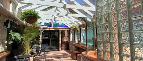 A covered outdoor area with a glass ceiling, stone walls, and potted plants.