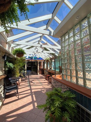 A covered outdoor area with a glass ceiling, stone walls, and potted plants. - Ettalong Beach Tourist Resort (Ettalong Beach)