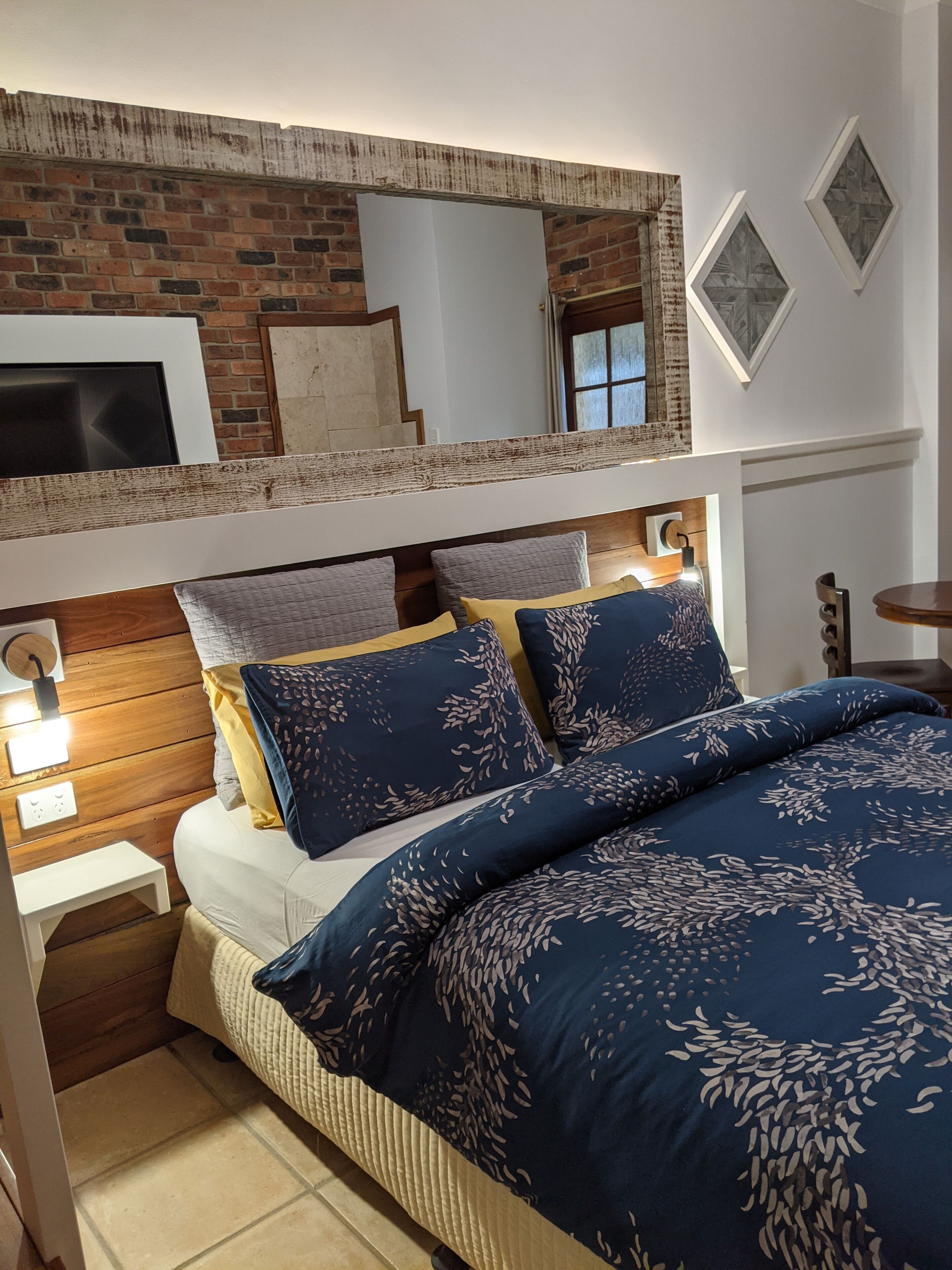 Una cama litera con cabecera de madera, una mesita de noche blanca y una mesita auxiliar.