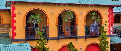 A building with a yellow facade, green roof, and multiple arched windows.