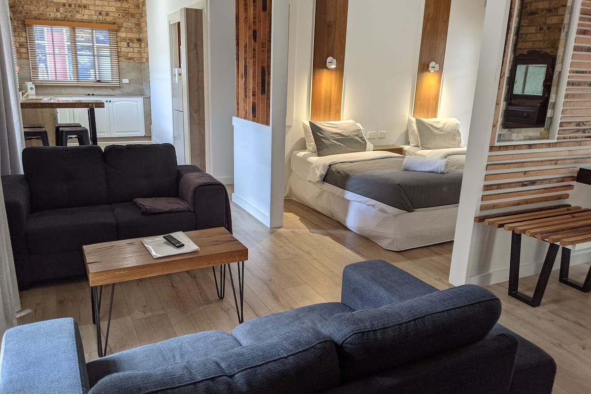Un salon moderne avec un canapé, une table basse et un coin repas près d’une fenêtre.