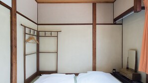 A simple, clean room with a bed, a wooden wardrobe, and a mirror.