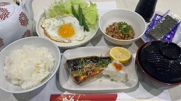 A table with various dishes including rice, fried egg, salad, beans, fish, and a lemon wedge.