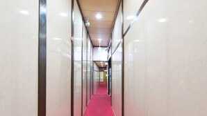 A corridor with a red carpet, glass walls, and ceiling lights.
