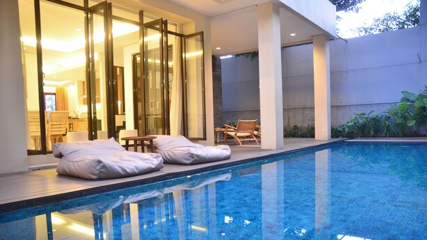 Ein Swimmingpool mit Liegestühlen und einer Glastür, die zu einem Raum führt.