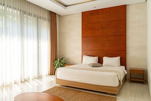 A modern bedroom with a large bed, a wooden headboard, a bedside table, and a potted plant.