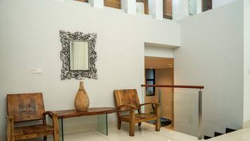 A modern interior with a wooden bench, a large mirror, and a vase.