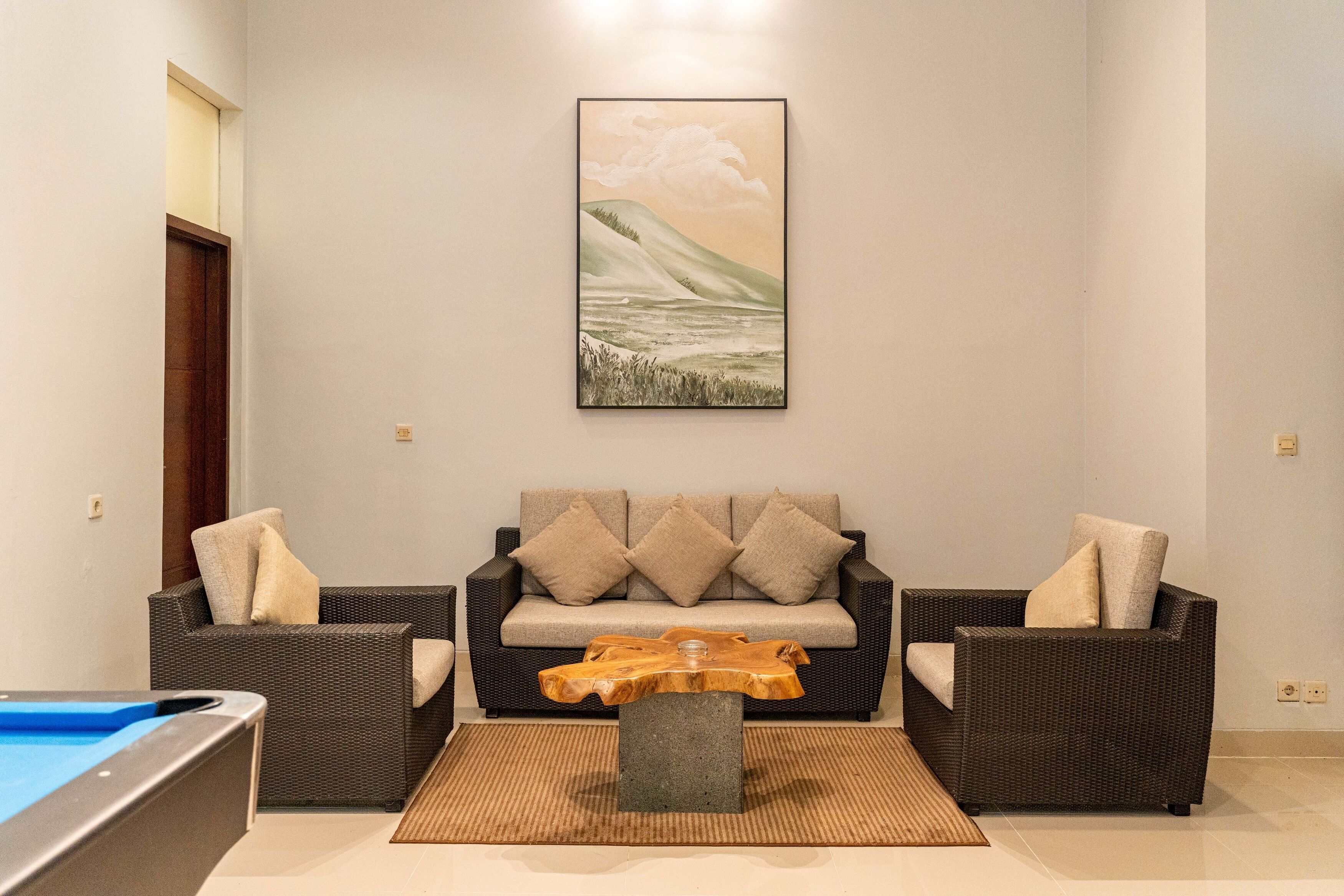 A living room with a sofa, two armchairs, a coffee table, and a painting on the wall.