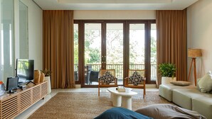 Ein modernes Wohnzimmer mit einer Couch, einem Couchtisch, einem Fernseher und einem Balkon mit Vorhängen.