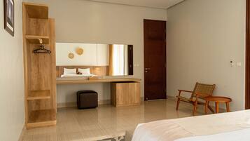 Une chambre d’hôtel moderne équipée d’un lit, d’un bureau en bois, d’une chaise, d’une armoire et d’un miroir.