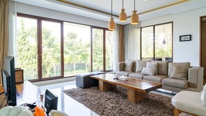 Ein modernes Wohnzimmer mit einer Couch, einem Couchtisch und großen Fenstern.