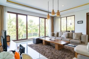Una sala de estar moderna con sofá, mesa de centro y ventanas amplias.