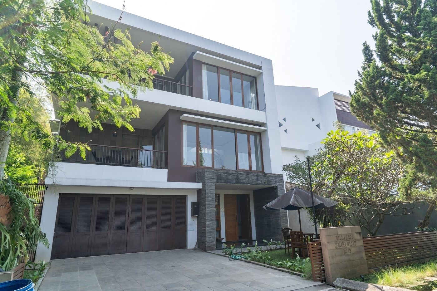 Ein modernes, zweistöckiges Haus mit Garage, großen Fenstern und einem Balkon.