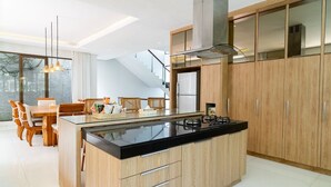 Eine moderne Küche mit einer zentralen Kochinsel, Holzschränken und einem Essbereich mit Stühlen und Tisch.