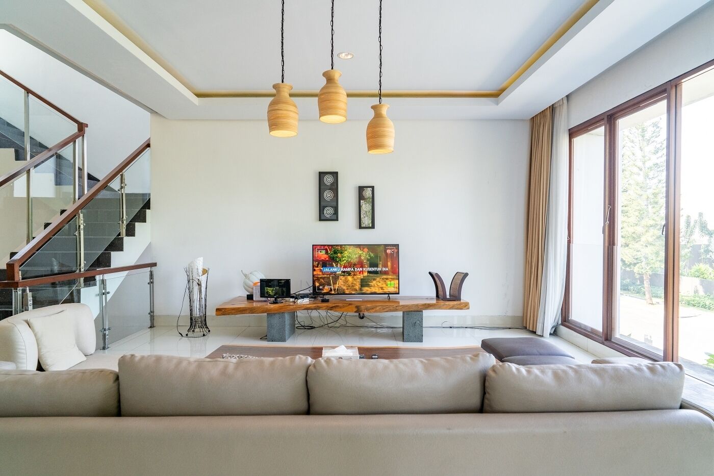 A modern living room with a sofa, TV, wooden coffee table, and pendant lights.