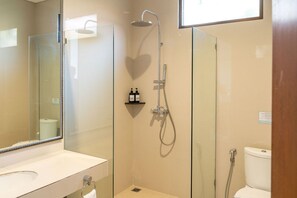 Un baño moderno con cabina de ducha de vidrio, inodoro blanco y tocador con espejo.