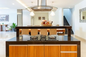 Cocina moderna con isla central, armarios empotrados y una lámpara colgante.
