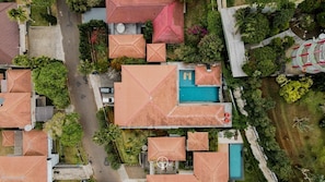 An aerial view of a residential area with multiple houses, a swimming pool, and a road.