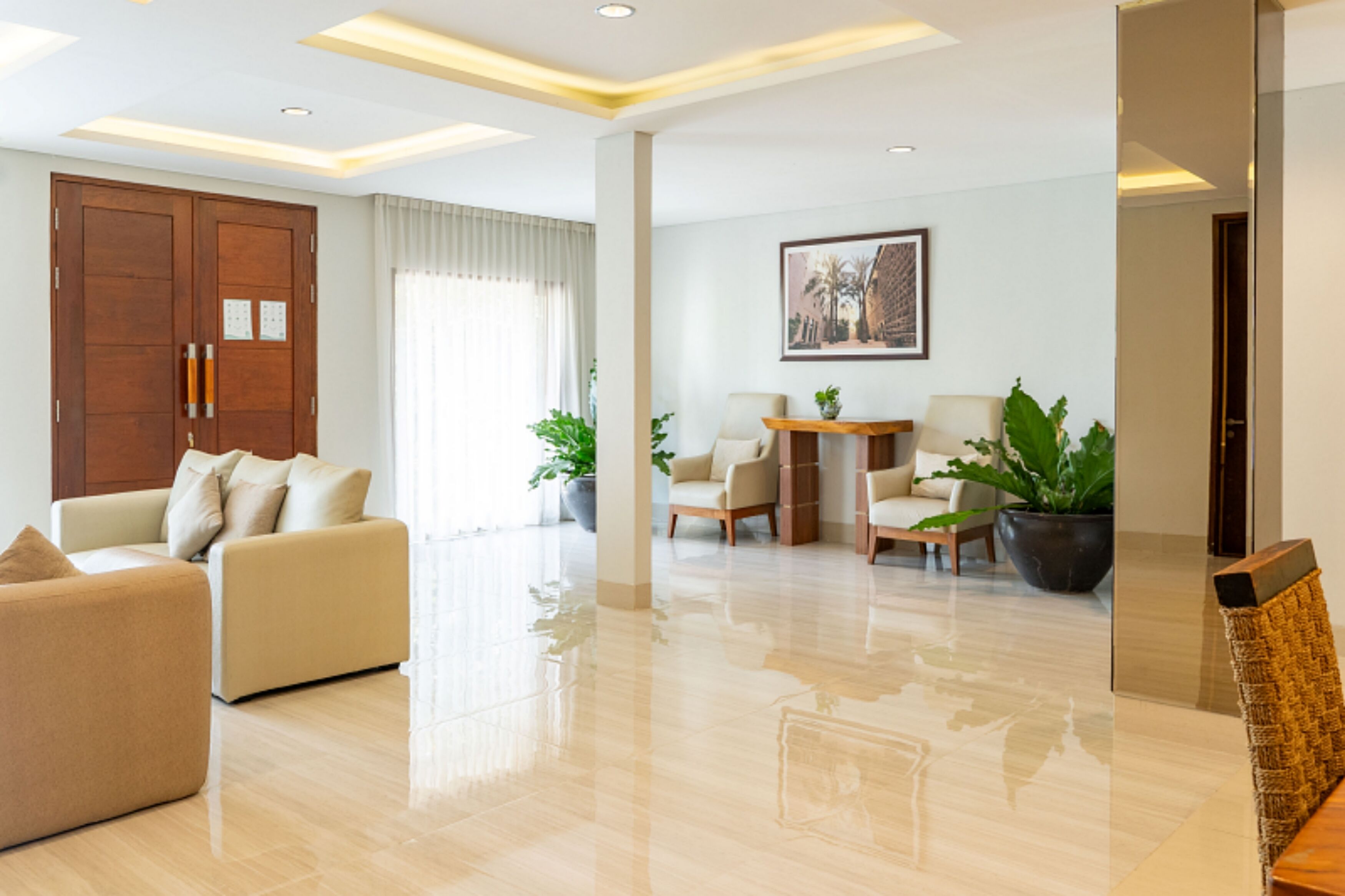 Amplia sala de estar con sofá, sillones, una mesita de centro y una mesa de comedor. Hay plantas en macetas y un cuadro en la pared.