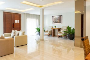 Amplia sala de estar con sofá, sillones, una mesita de centro y una mesa de comedor. Hay plantas en macetas y un cuadro en la pared.