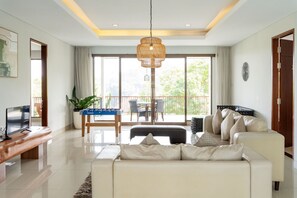 Una sala moderna con un sofá, una mesa de centro, un televisor y un balcón con una mesa y sillas.