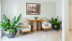 Una habitación moderna con dos sillas, una mesita y plantas grandes en macetas.