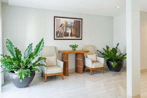 A modern room with two chairs, a small table, and large potted plants. - Kirei Mountain View Villa 7 Br With Heated Pool (Bandung)