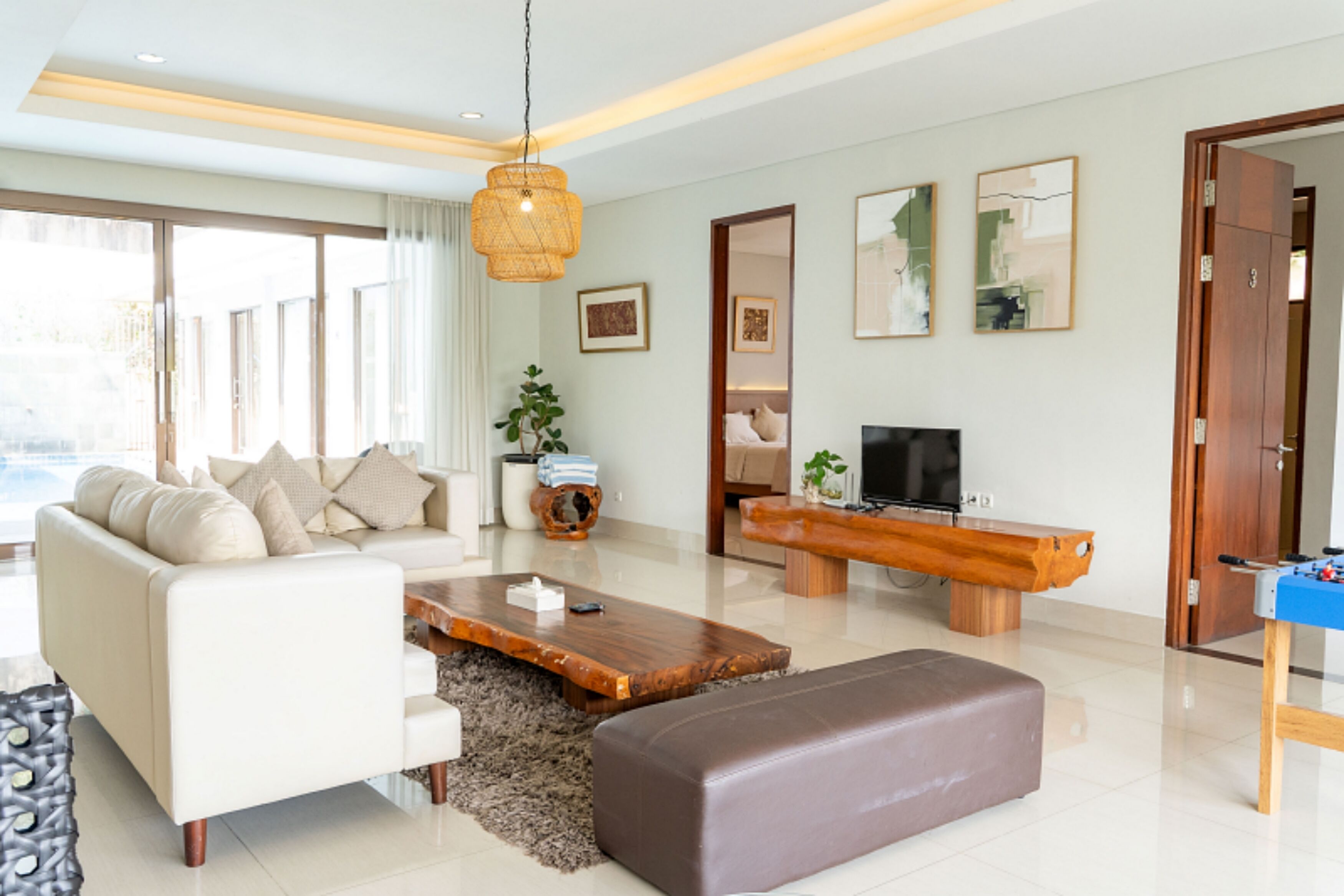 Una sala de estar moderna con un sofá, una mesa de centro, televisor y un banco de madera.