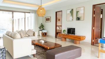 Una sala de estar moderna con un sofá, una mesa de centro, televisor y un banco de madera.