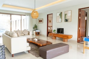 Una sala de estar moderna con un sofá, una mesa de centro, televisor y un banco de madera.